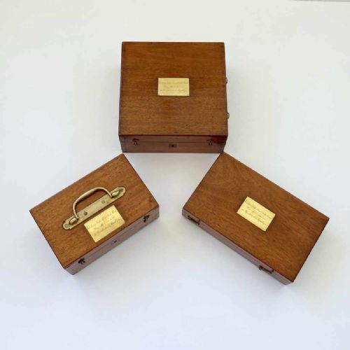 fig 1. An antique French marine navigation set displayed in three open fitted mahogany cases containing a brass sextant, telescopes, and optical filters.