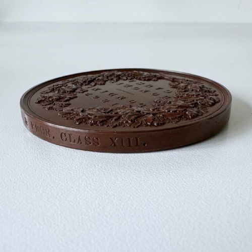 fig 5. A circular Victorian bronze exhibition medallion depicting classical allegorical figures, Britannia, and a reclining lion in high relief.
