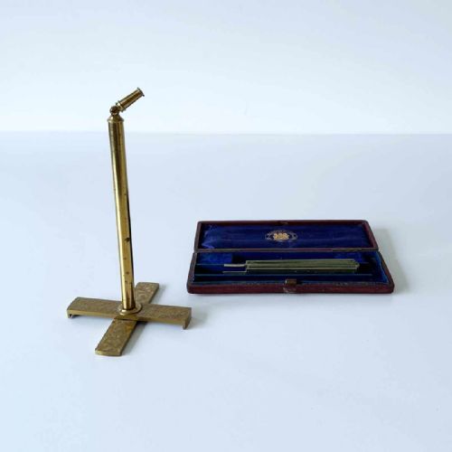 fig 1. An antique Victorian brass microscopy candle shade with a pleated green fan screen standing beside its original velvet-lined presentation case.