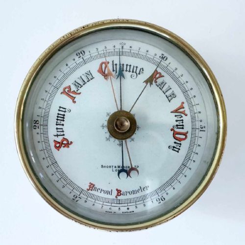fig 4. A circular brass wall-hanging aneroid barometer featuring a silvered dial with Gothic lettering, calibrated scale, and multiple indicator pointers.