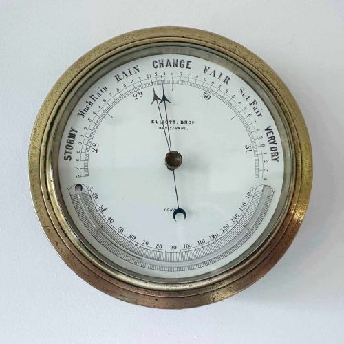 fig 5. A circular Victorian brass aneroid barometer featuring a white enamel dial with black atmospheric pressure readings and blued steel hands.