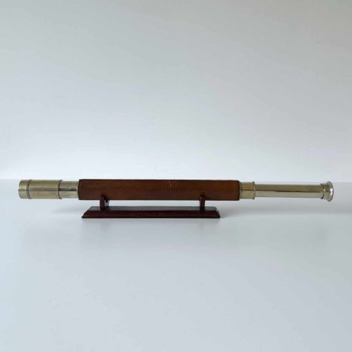fig 1. A Victorian brass single draw marine telescope with a brown hexagonal barrel mounted on a dark wooden display stand.
