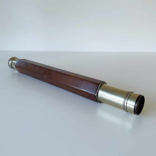 fig 2. A Victorian brass single draw marine telescope with a brown hexagonal barrel mounted on a dark wooden display stand.