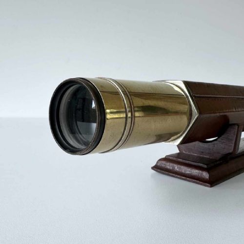 fig 5. A Victorian brass single draw marine telescope with a brown hexagonal barrel mounted on a dark wooden display stand.
