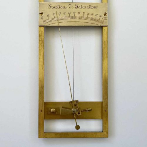 fig 5. A rectangular brass-framed Saussure hair hygrometer featuring engraved text plates and a curved graduated scale with a pointer needle.