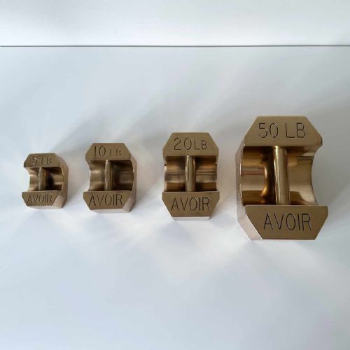 fig 1. A set of four graduated Edwardian brass avoirdupois standard weights displaying engraved weight values ranging from five to fifty pounds.