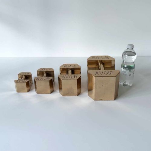 fig 2. A set of four graduated Edwardian brass avoirdupois standard weights displaying engraved weight values ranging from five to fifty pounds.