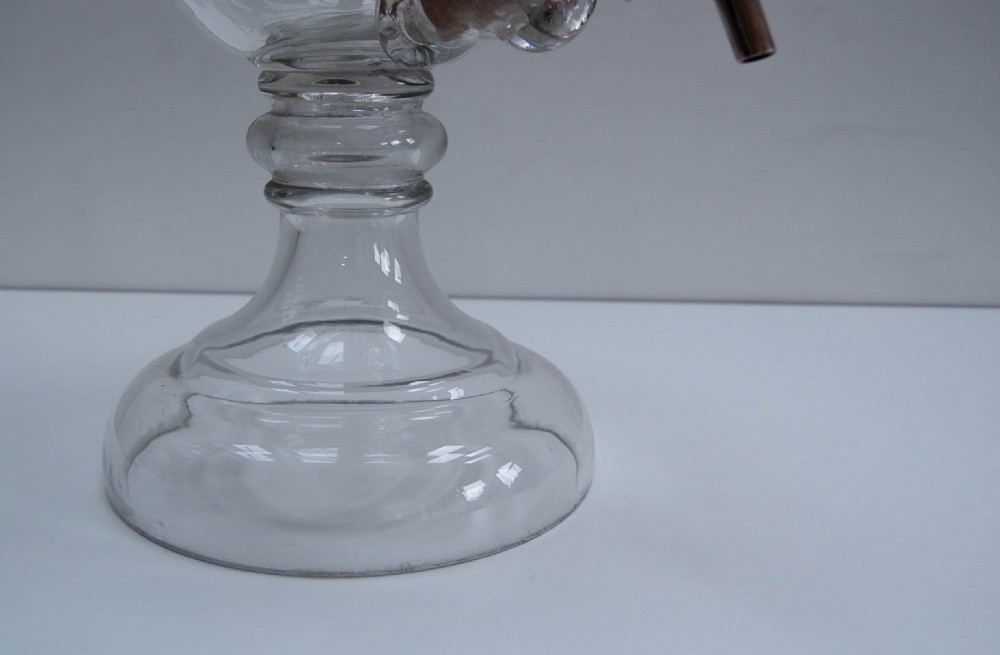 A clear glass spirit dispenser featuring gilt typography reading Fine Pale Brandy, a spire finial lid, and a brass spigot at the base. View VII