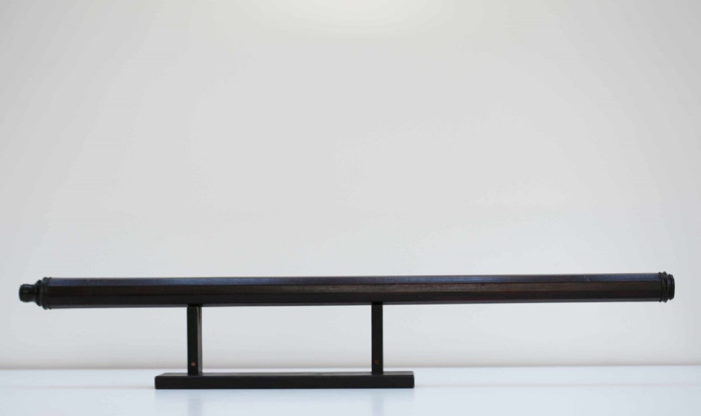 A mid-eighteenth-century dark mahogany decagonal optical telescope mounted horizontally on a matching dark wooden display stand.