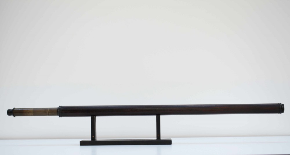 A mid-eighteenth-century dark mahogany decagonal optical telescope mounted horizontally on a matching dark wooden display stand. View II