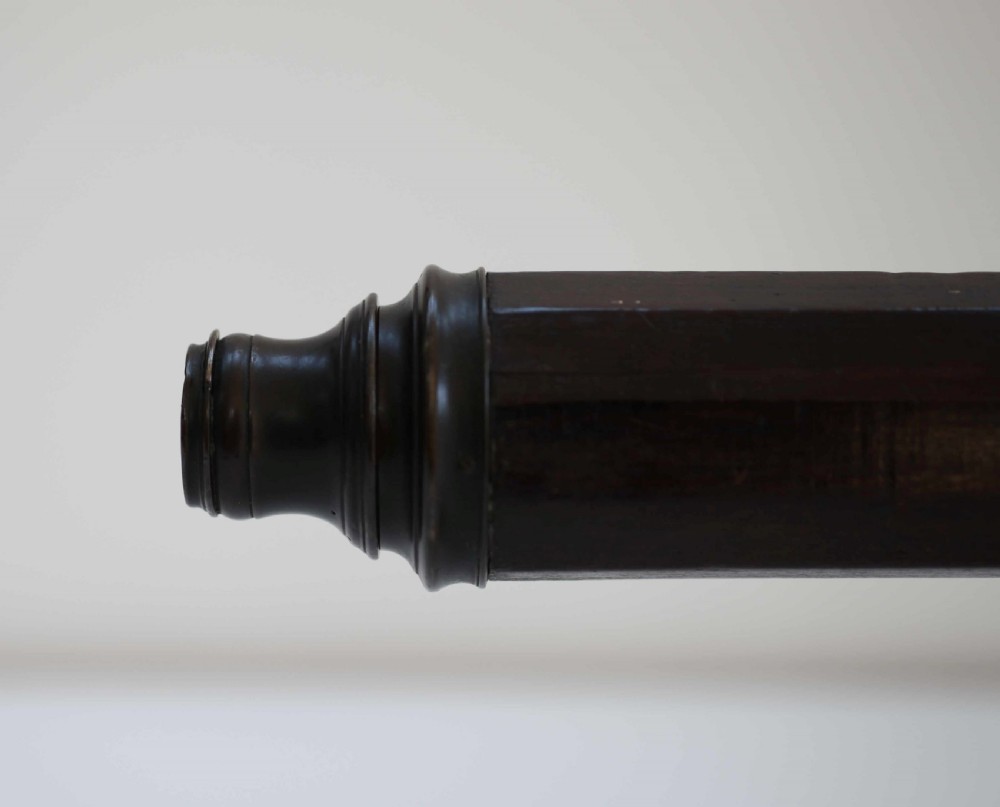 A mid-eighteenth-century dark mahogany decagonal optical telescope mounted horizontally on a matching dark wooden display stand. View VI