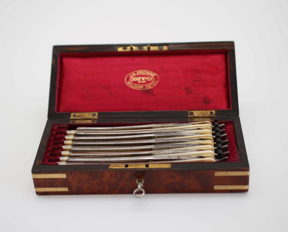 A rectangular burr walnut box featuring brass corner straps, a brass nameplate cartouche on the lid, and a key inserted into the front keyhole. View II