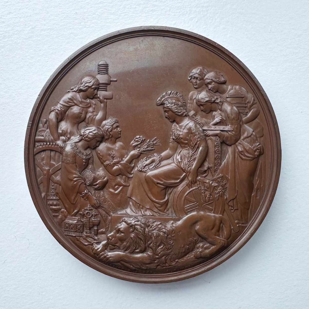 A circular Victorian bronze exhibition medallion depicting classical allegorical figures, Britannia, and a reclining lion in high relief.