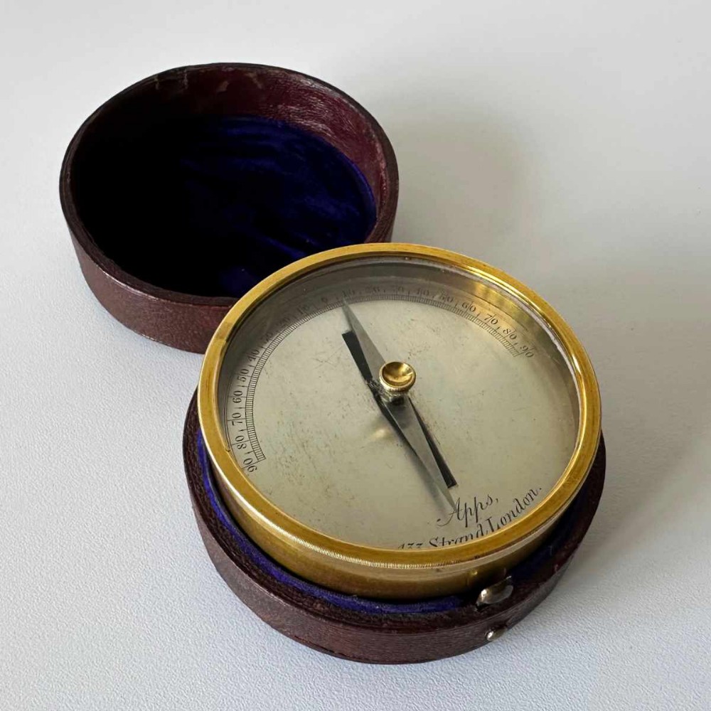 A Victorian brass pocket galvanometer with a silvered dial housed inside a open dark leather protective case lined with blue velvet.