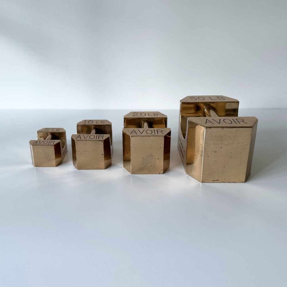 A set of four graduated Edwardian brass avoirdupois standard weights displaying engraved weight values ranging from five to fifty pounds.
