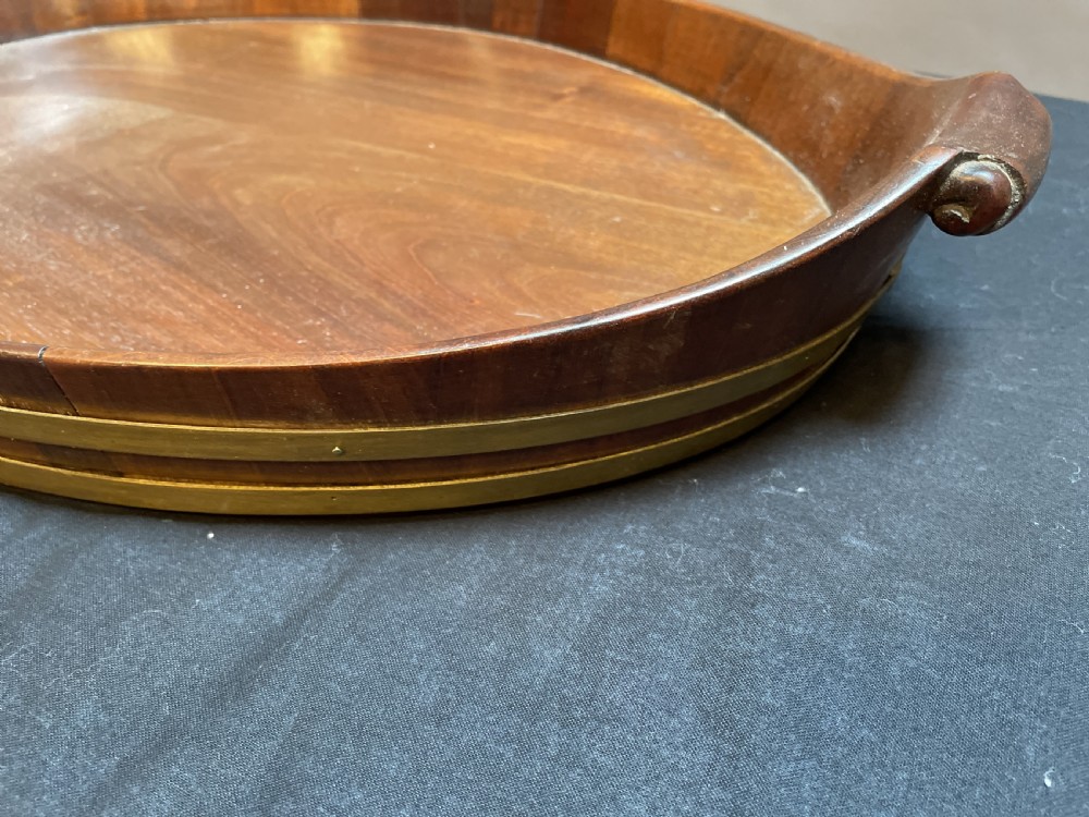 A Georgian Revival oval mahogany serving tray featuring a raised rim, integrated handles, and a brass band outer trim. View IV