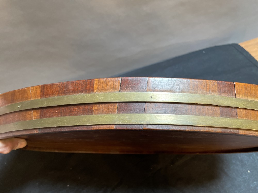 A Georgian Revival oval mahogany serving tray featuring a raised rim, integrated handles, and a brass band outer trim. View V