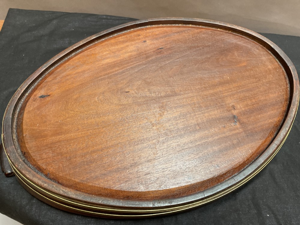A Georgian Revival oval mahogany serving tray featuring a raised rim, integrated handles, and a brass band outer trim. View VII
