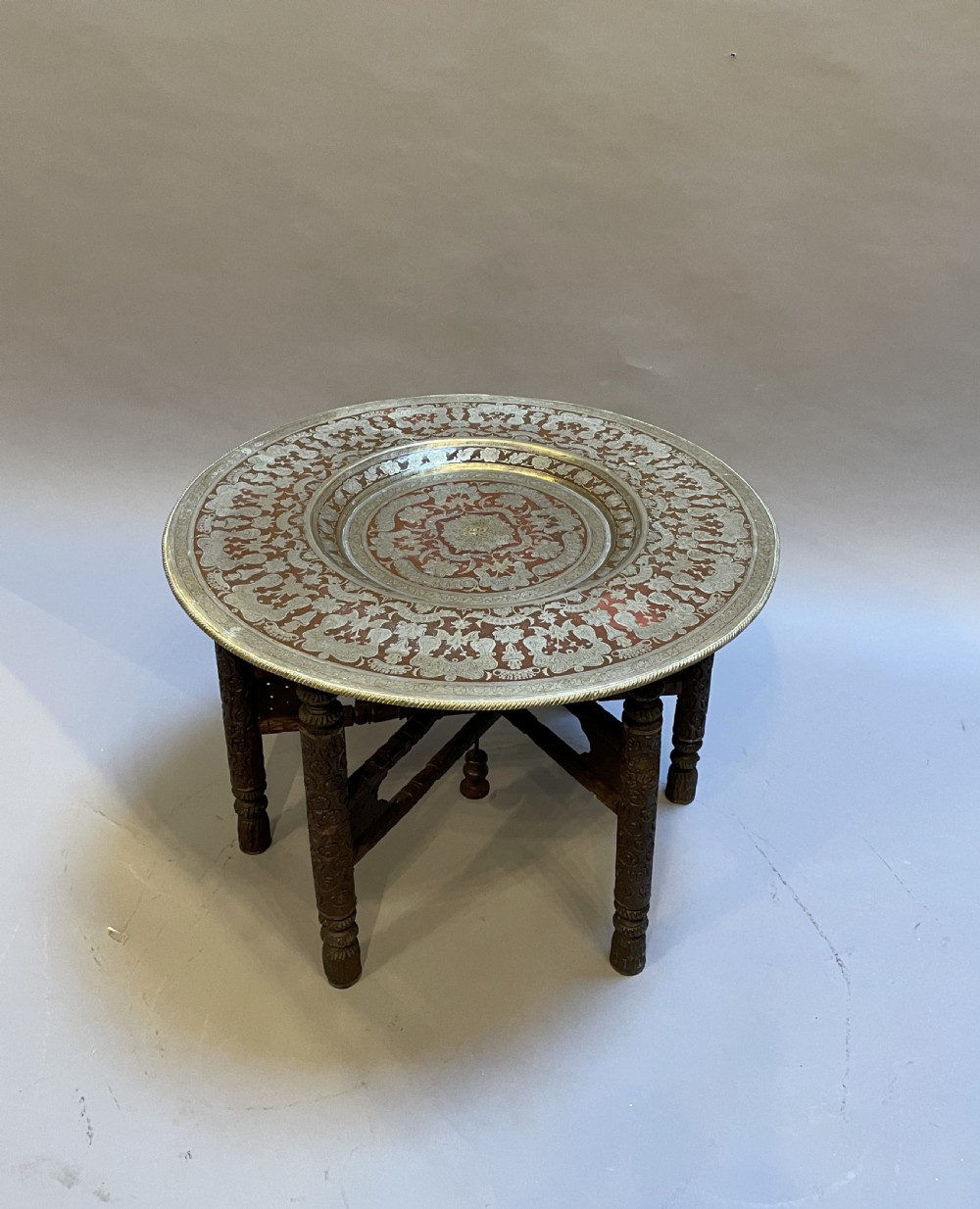 A low circular occasional table featuring an intricately etched multi-metal tray top resting on a dark carved wooden base. View IV