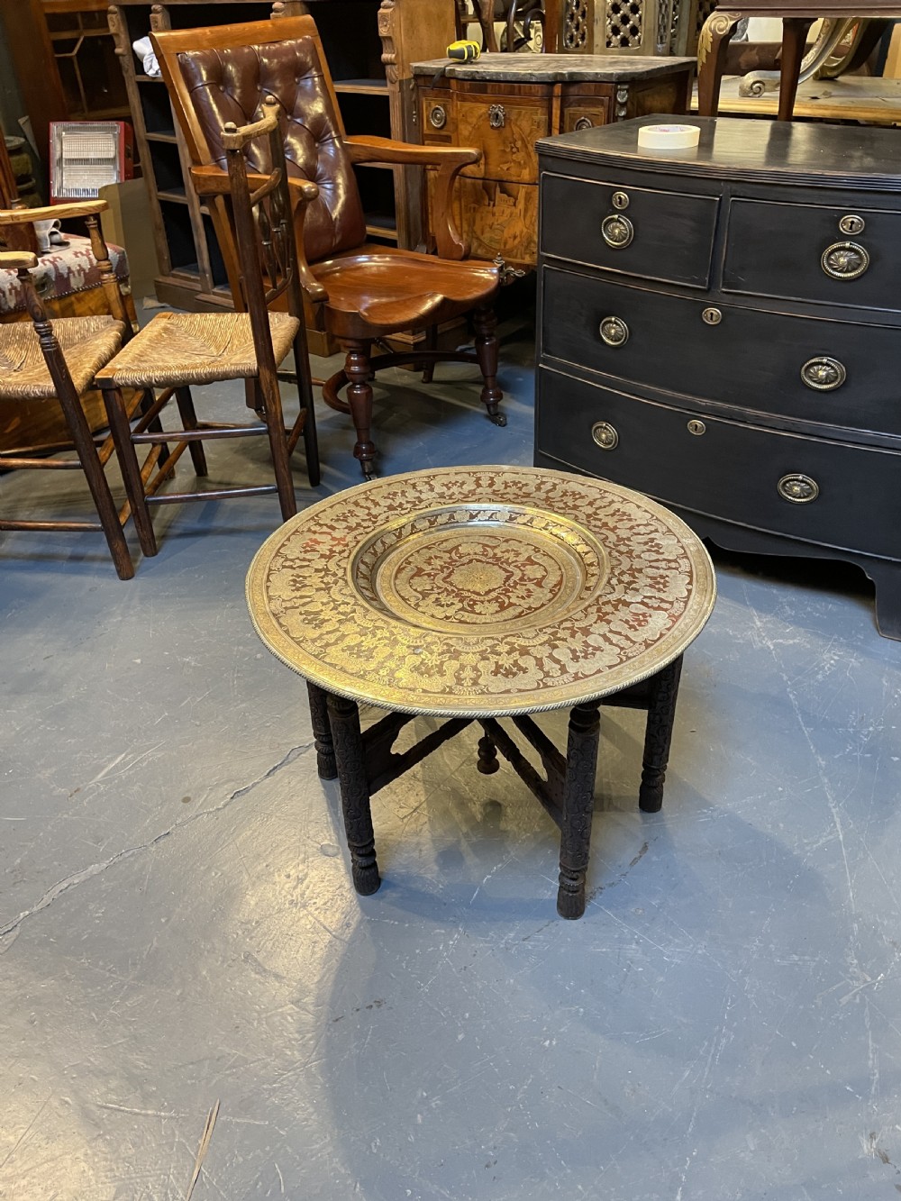 A low circular occasional table featuring an intricately etched multi-metal tray top resting on a dark carved wooden base. View VI