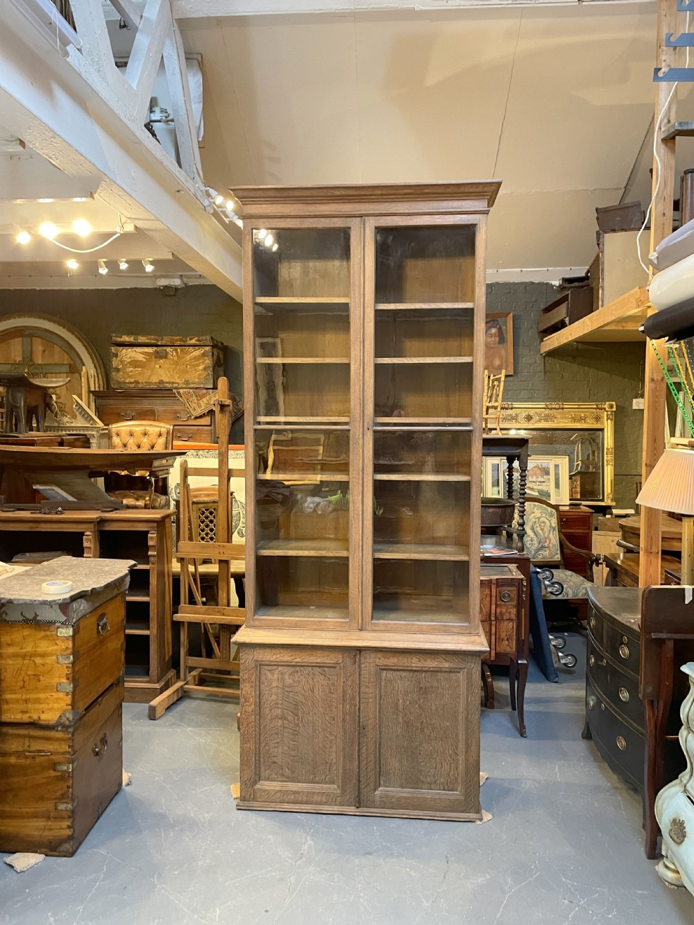 A tall Victorian light oak two-part bookcase with two upper glazed doors revealing adjustable shelves and a two-door cupboard base. View XXIII