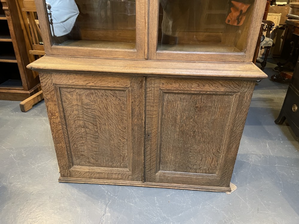 A tall Victorian light oak two-part bookcase with two upper glazed doors revealing adjustable shelves and a two-door cupboard base. View XXIV
