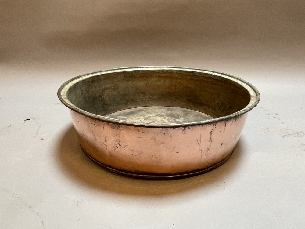 A large nineteenth-century circular copper preserve pan featuring flared sides, a rolled rim, and an aged interior showing signs of historical wear.