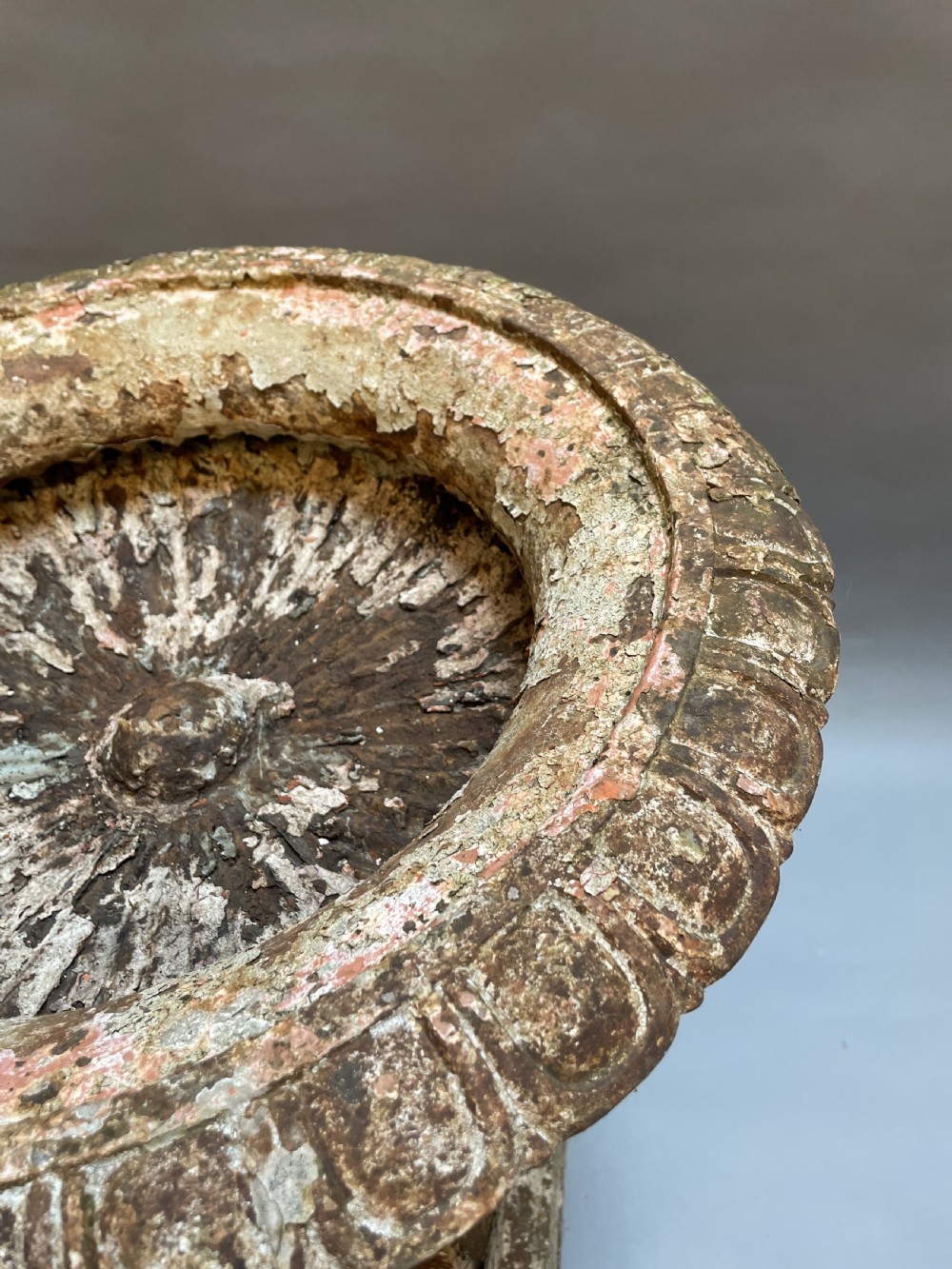 A Victorian cast iron garden urn with a fluted rim and laurel wreath medallion base, displaying a weathered white paint finish over oxidised iron. View III