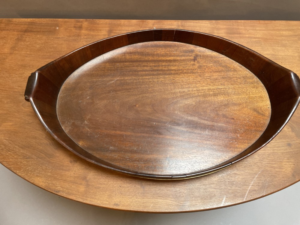 A Georgian Revival oval mahogany serving tray featuring a raised rim, integrated handles, and a brass band outer trim. View II
