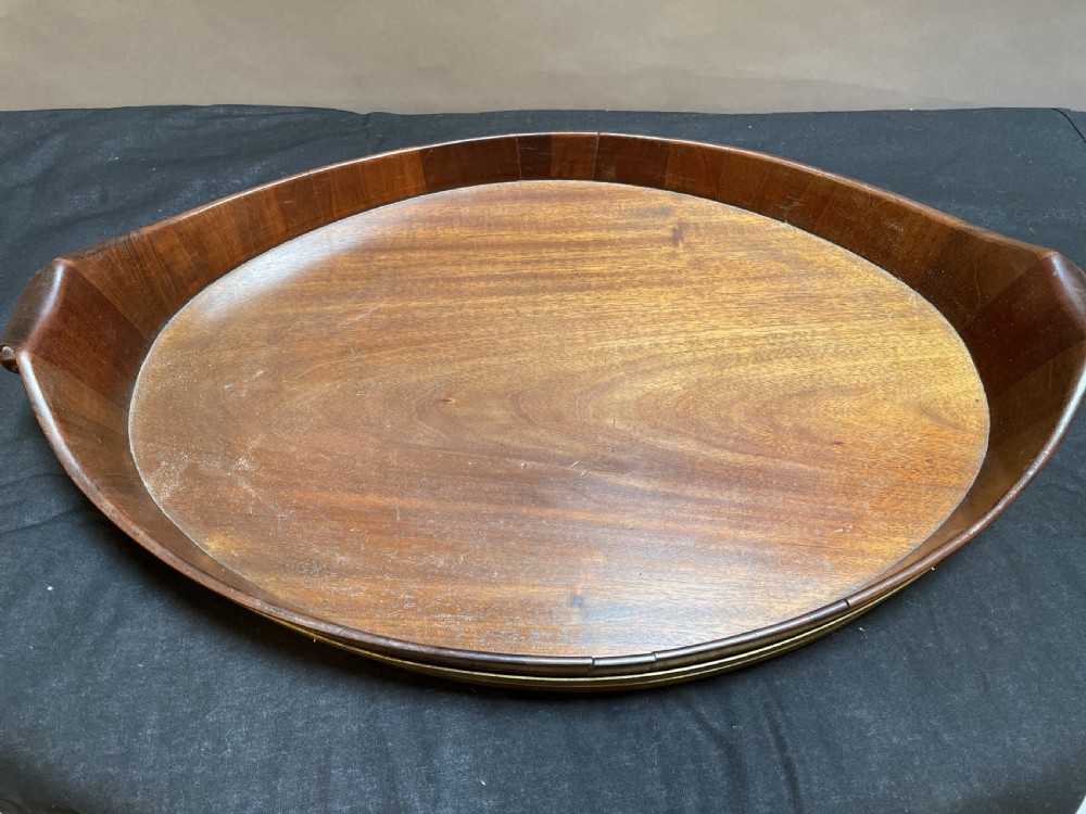 A Georgian Revival oval mahogany serving tray featuring a raised rim, integrated handles, and a brass band outer trim. View III