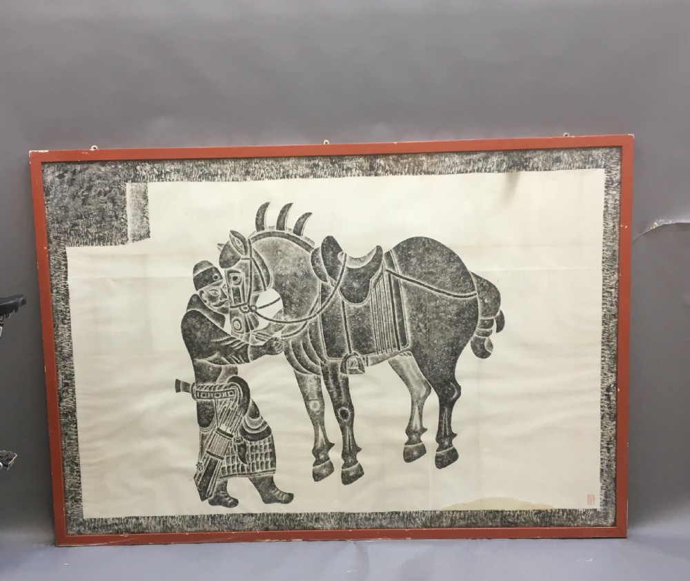 A large monochrome framed paper rubbing depicting a groom attending to a saddled Tang Dynasty horse. View V