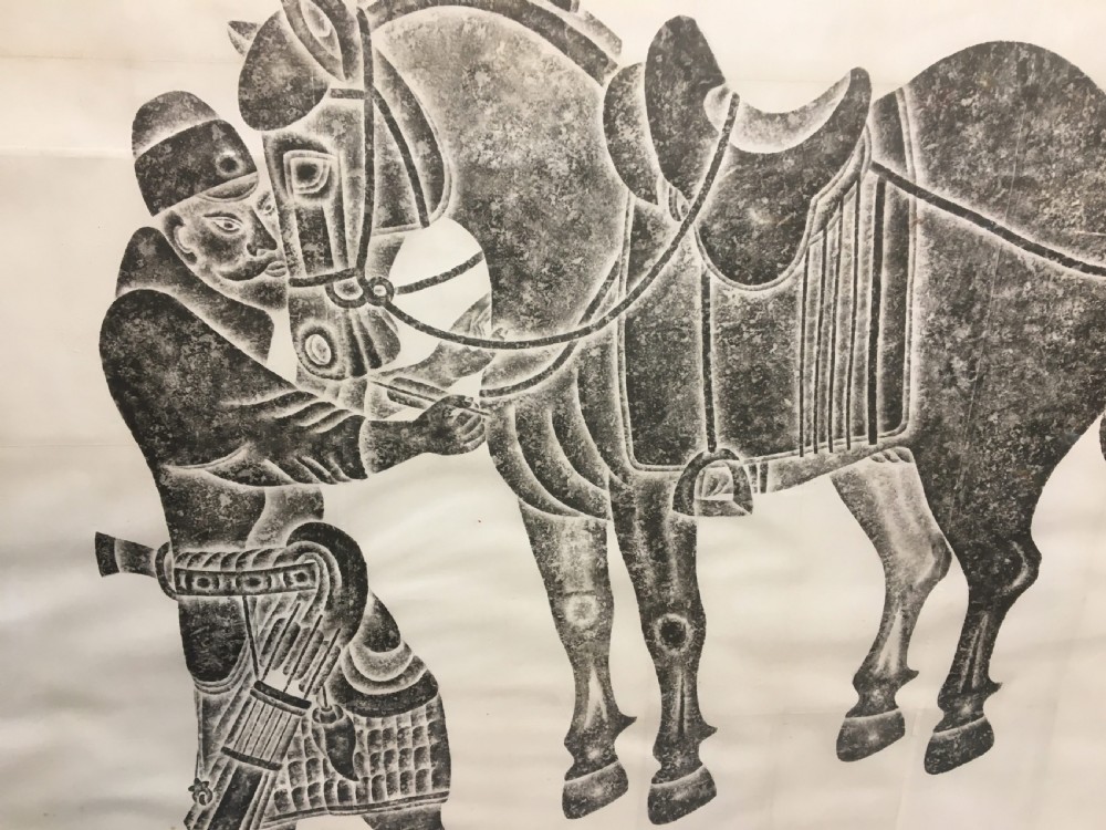 A large monochrome framed paper rubbing depicting a groom attending to a saddled Tang Dynasty horse. View XIV
