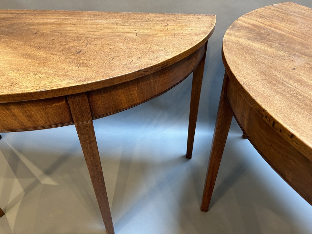 A pair of George III mahogany semi-circular demilune console tables supported by square tapered legs. View III