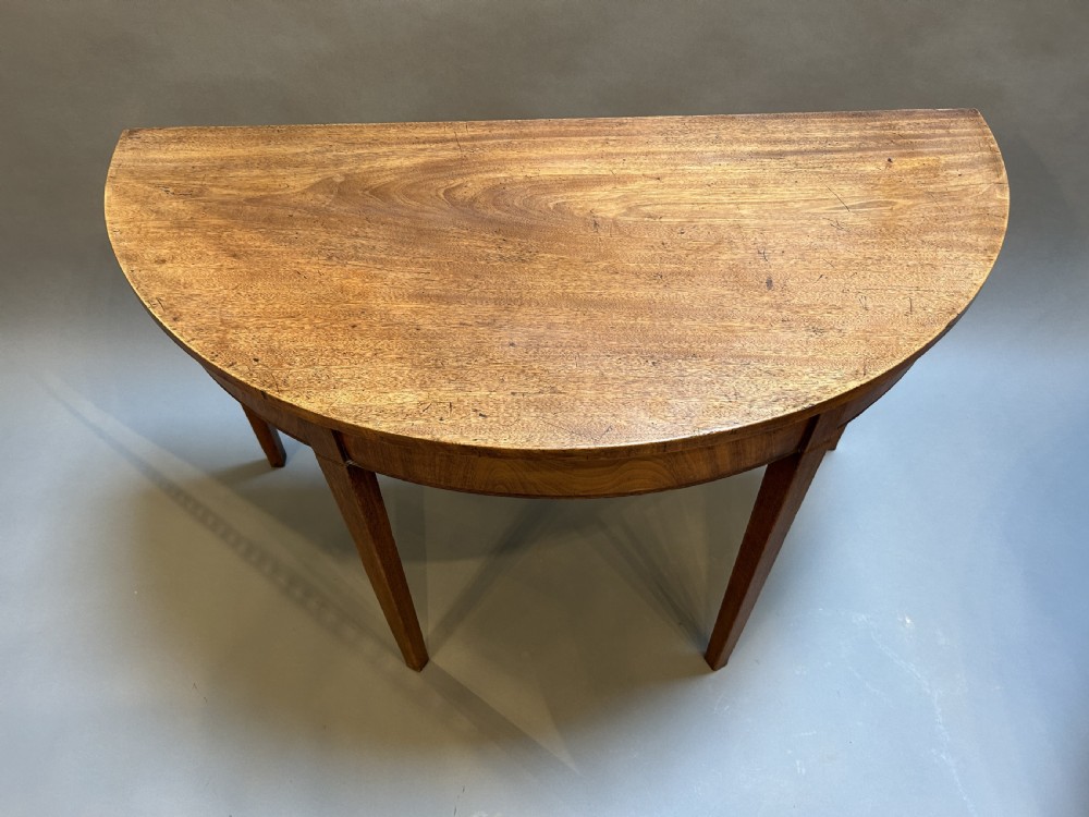 A pair of George III mahogany semi-circular demilune console tables supported by square tapered legs. View IV