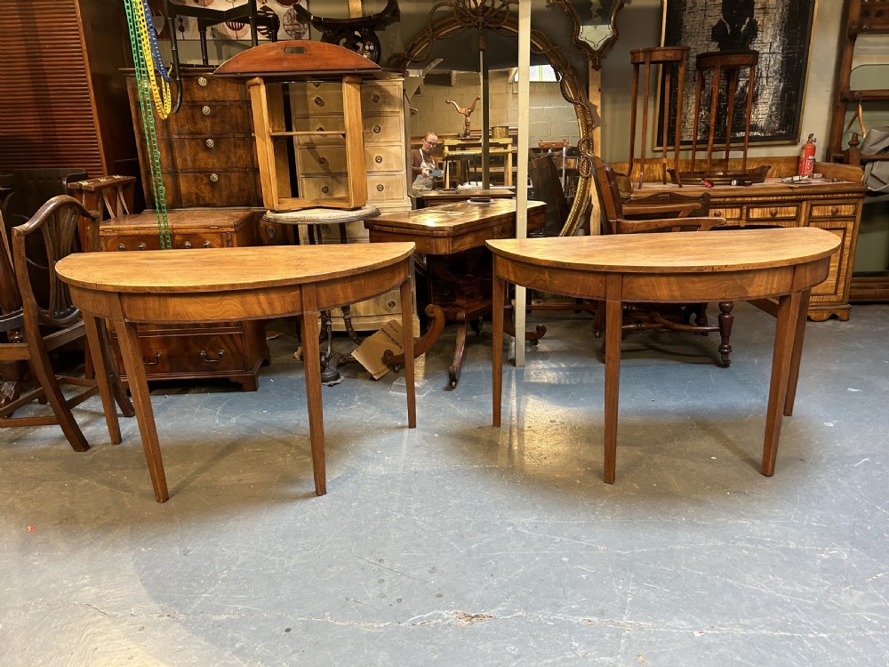 A pair of George III mahogany semi-circular demilune console tables supported by square tapered legs. View V