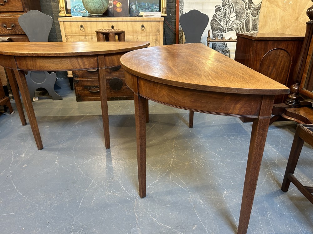 A pair of George III mahogany semi-circular demilune console tables supported by square tapered legs. View VI