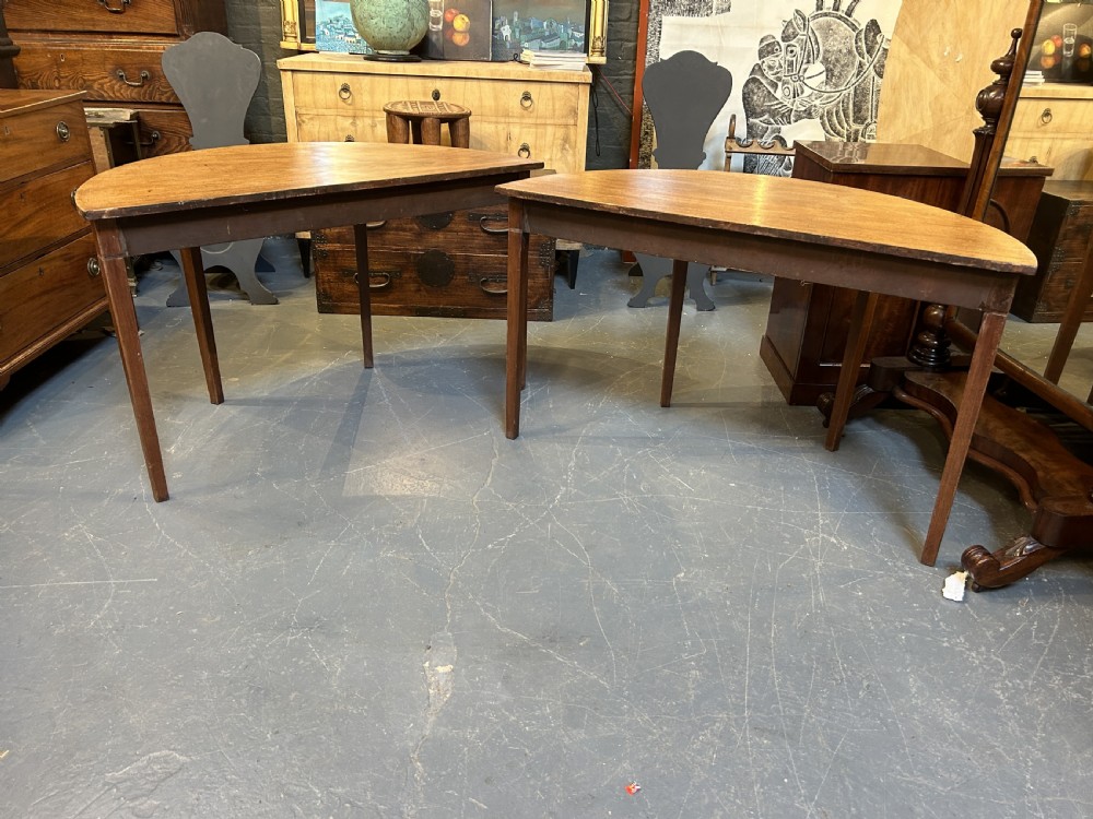 A pair of George III mahogany semi-circular demilune console tables supported by square tapered legs. View VII