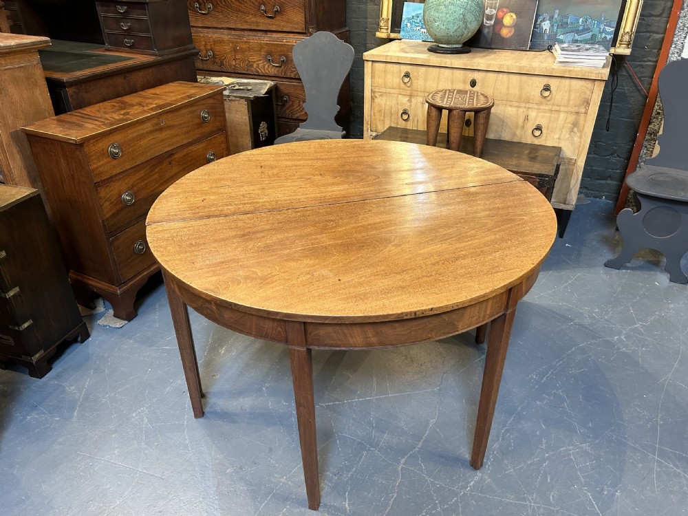 A pair of George III mahogany semi-circular demilune console tables supported by square tapered legs. View VIII