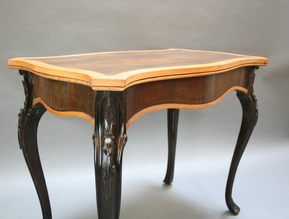 A 19th-century Ceylonese serpentine centre table featuring dark hardwood construction, a light wood crossbanded top, and carved cabriole legs. View V