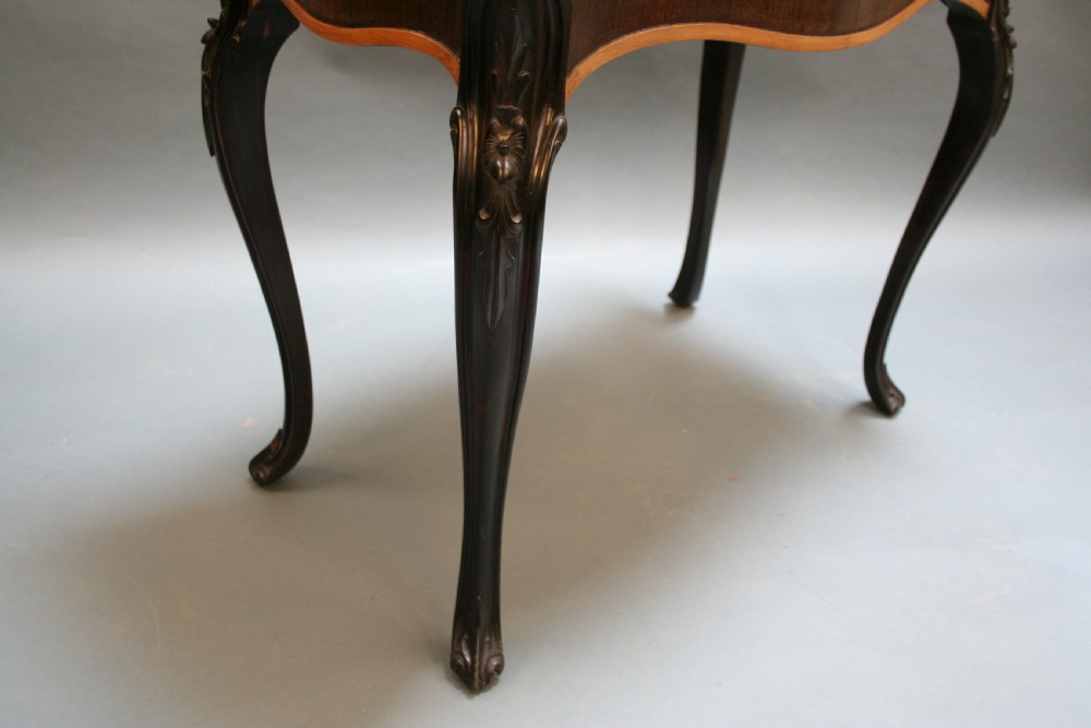 A 19th-century Ceylonese serpentine centre table featuring dark hardwood construction, a light wood crossbanded top, and carved cabriole legs. View VI