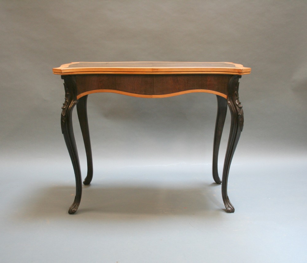 A 19th-century Ceylonese serpentine centre table featuring dark hardwood construction, a light wood crossbanded top, and carved cabriole legs. View VII