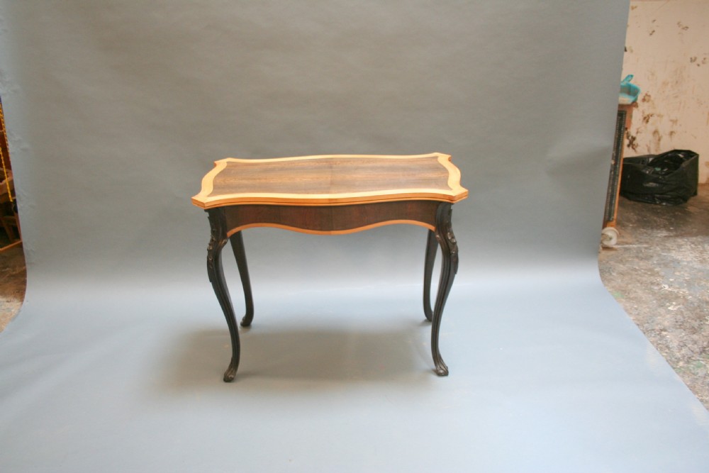 A 19th-century Ceylonese serpentine centre table featuring dark hardwood construction, a light wood crossbanded top, and carved cabriole legs. View VIII