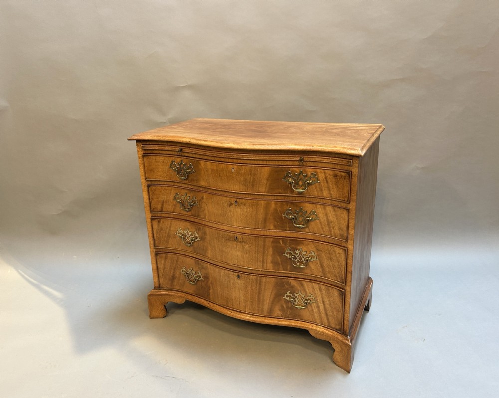A 19th-century mahogany chest of drawers featuring a serpentine front, four graduated drawers with ornamental brass handles, and bracket feet.