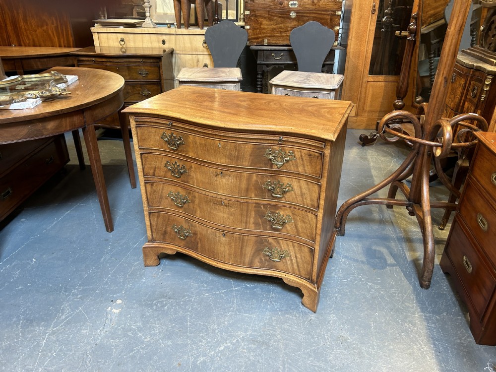 A 19th-century mahogany chest of drawers featuring a serpentine front, four graduated drawers with ornamental brass handles, and bracket feet. View III
