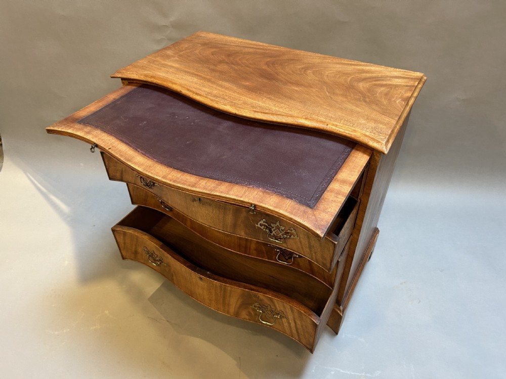 A 19th-century mahogany chest of drawers featuring a serpentine front, four graduated drawers with ornamental brass handles, and bracket feet. View VIII