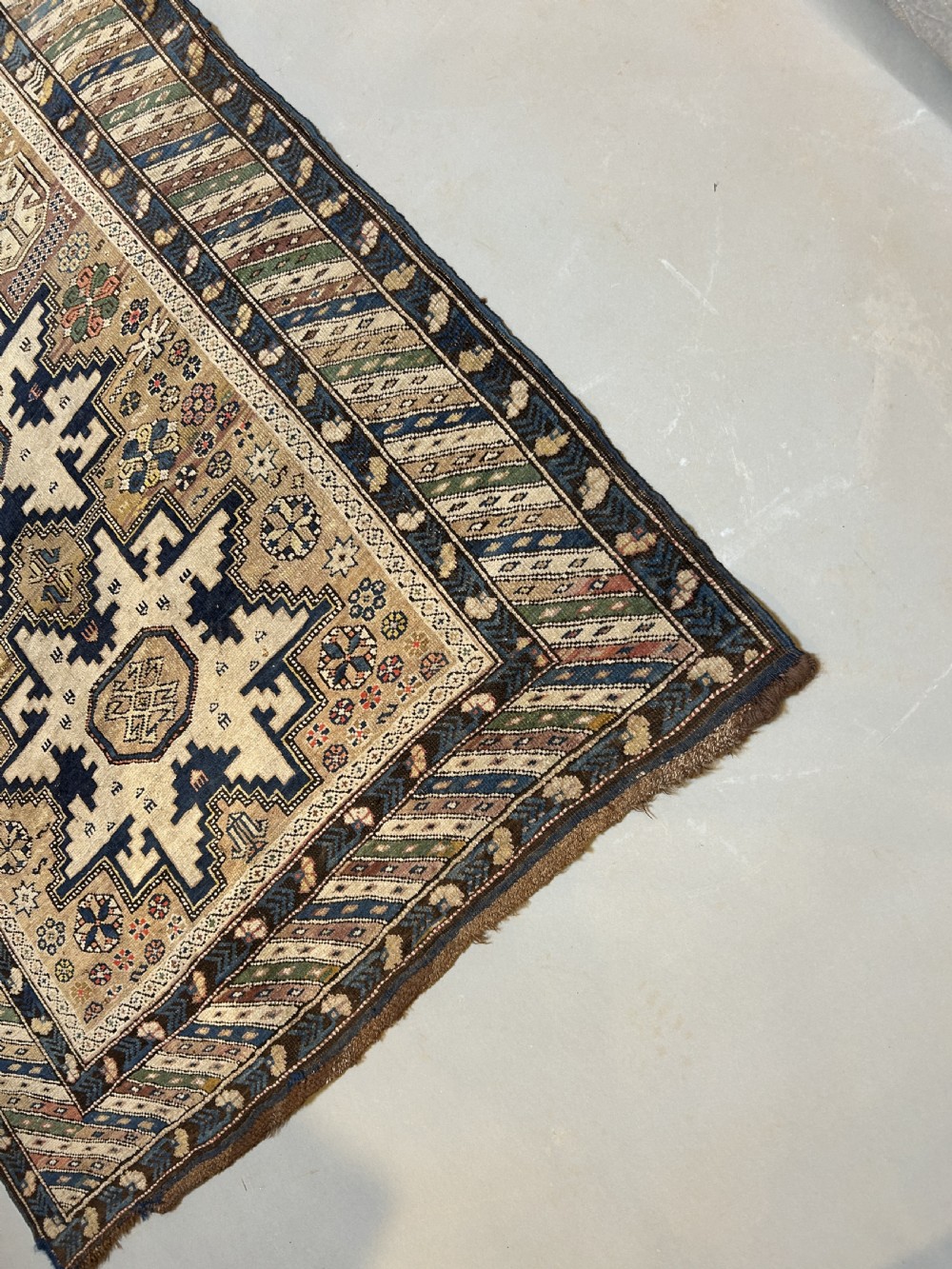 An antique Caucasian Kazak wool rug featuring three cream latch-hook medallions on a terracotta red field with geometric borders. View II