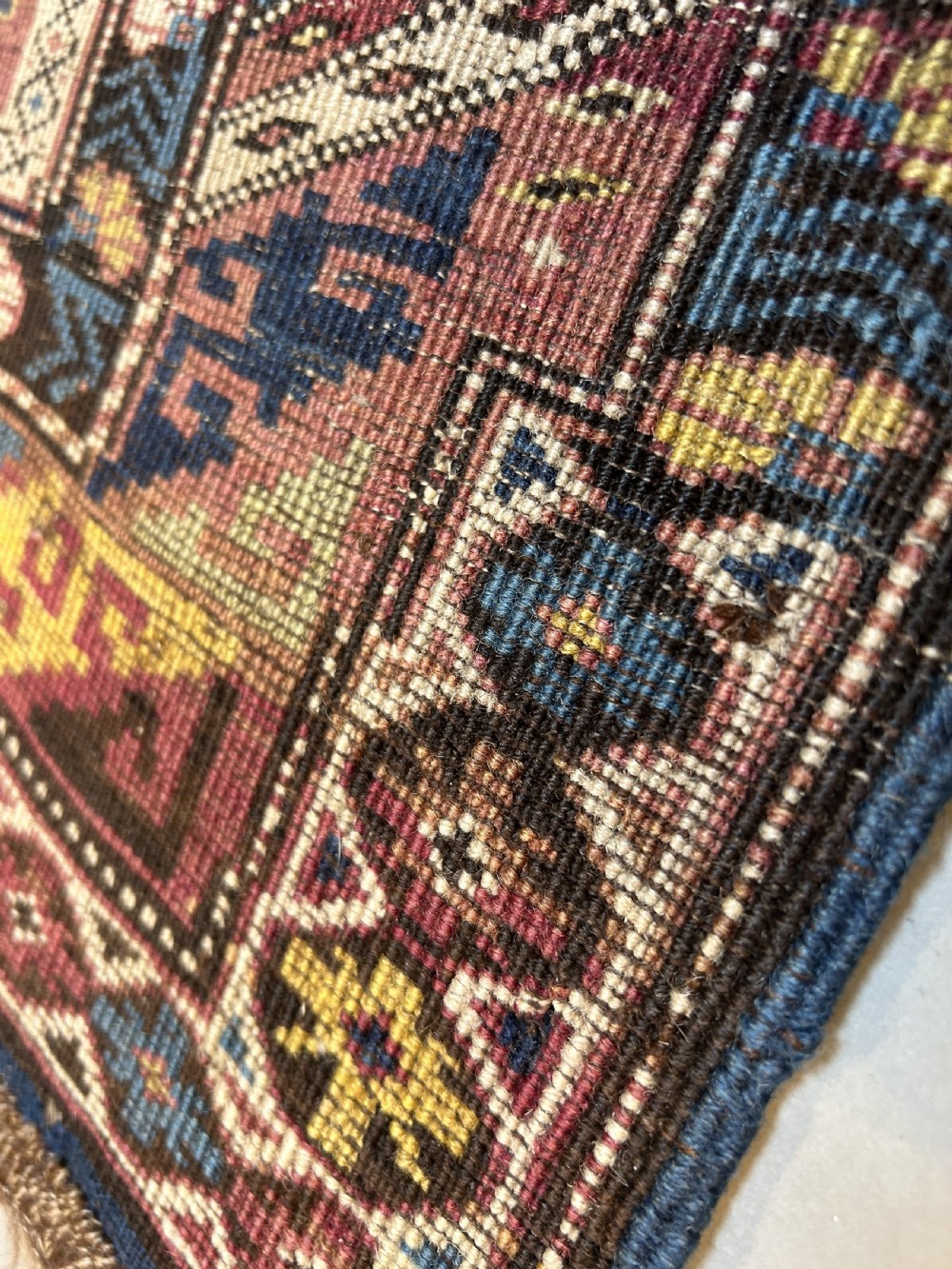 An antique Caucasian Kazak wool rug featuring three cream latch-hook medallions on a terracotta red field with geometric borders. View IV