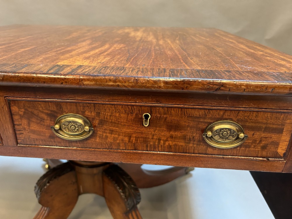 A George IV mahogany sofa table featuring drop leaves, frieze drawers with brass handles, and a reeded quadruped pedestal base with brass castors. View IV