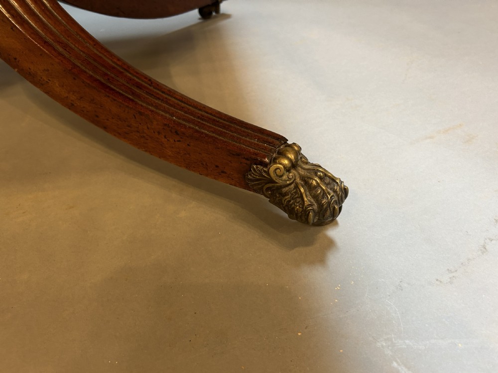 A George IV mahogany sofa table featuring drop leaves, frieze drawers with brass handles, and a reeded quadruped pedestal base with brass castors. View VII