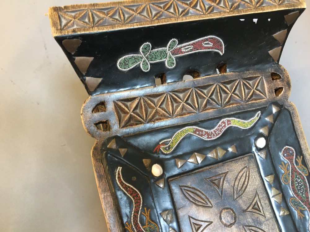 A hand-carved dark timber Ashanti stool featuring a curved seat with inlaid motifs, a central openwork column, and a rectangular carved base. View III